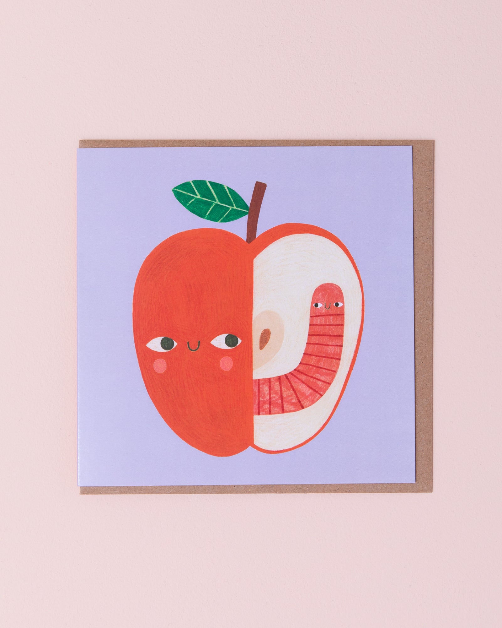 Daria Solak illustrated greetings card with brown kraft envelope. Red apple with a smiling face with a worm on a blue background.