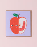 Daria Solak illustrated greetings card with brown kraft envelope. Red apple with a smiling face with a worm on a blue background.