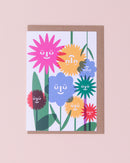 Lottie Hall illustration greetings card in blue, yellow, red, green and pink with a brown kraft envelope . Flowers with smiling faces.